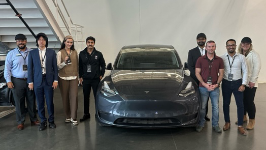 students and staff pose beside a Tesla Model Y while on a Career Trek to Tesla Gigafactory and HQ in Austin
